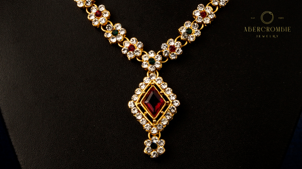 gold necklace with diamond, garnet, and emerald stones.
